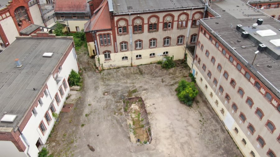 Luftaufnahme eines befestigten Wirtschaftshofs zwischen mehreren Gebäudeflügeln