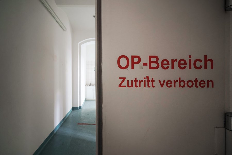 Tür mit roter Aufschrift OP-Bereich Zutritt verboten, dahinter ein heller Flur