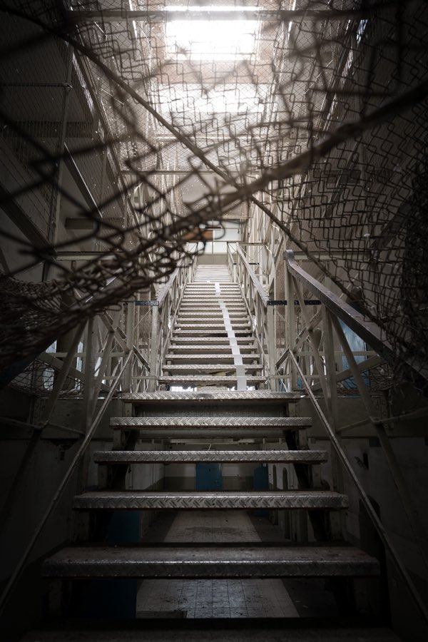 Metalltreppe von unten fotografiert, umgeben von durchhängenden Fangnetzen